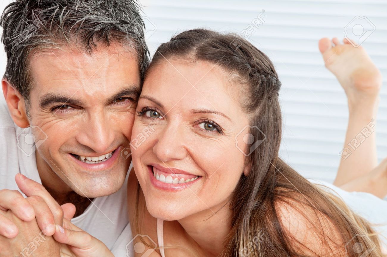 12108870-happy-smiling-senior-couple-laying-laughing-in-bed-stock-photo